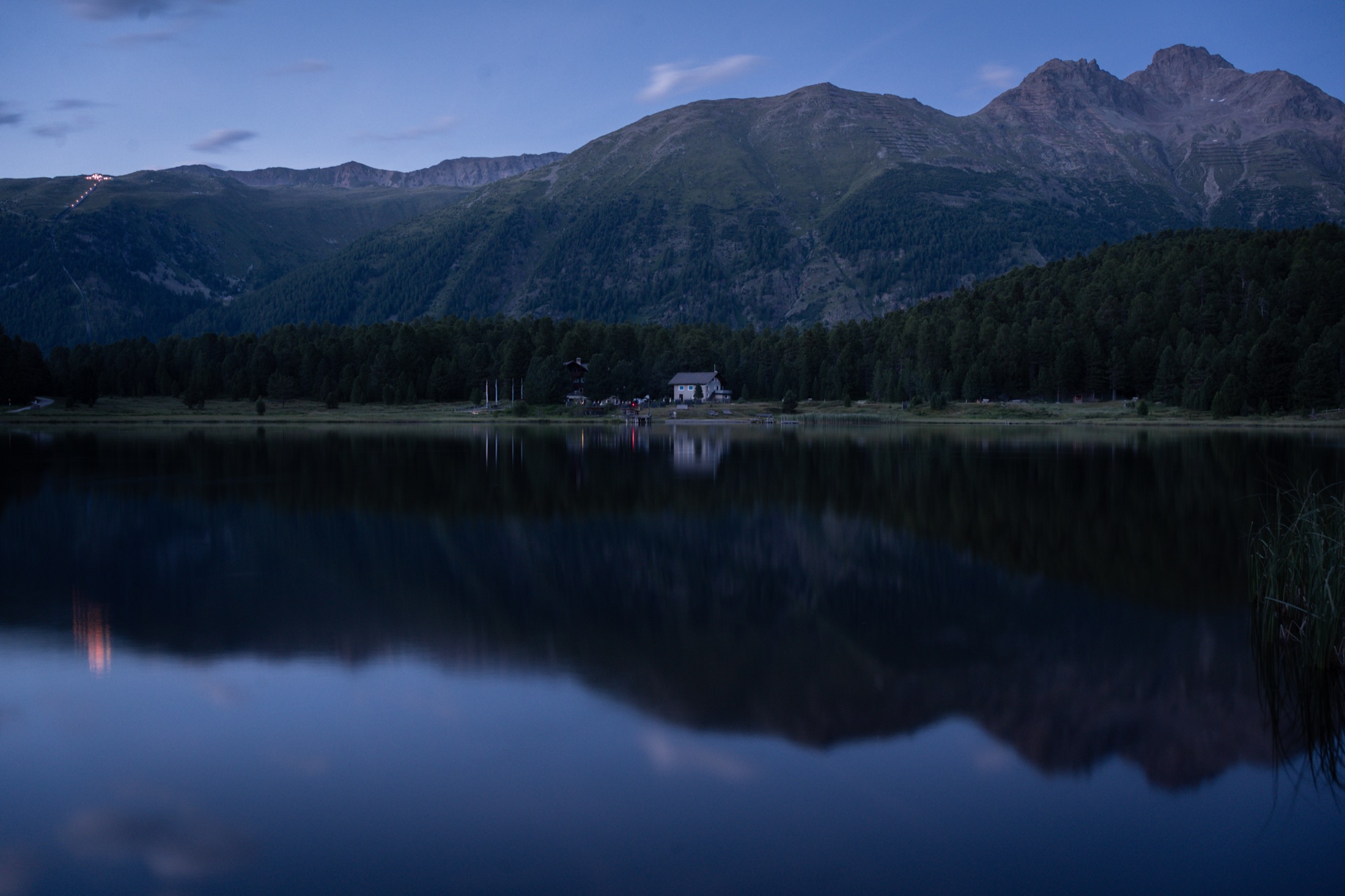 Blue-hour reflection of the mountains on a still Engadin lake