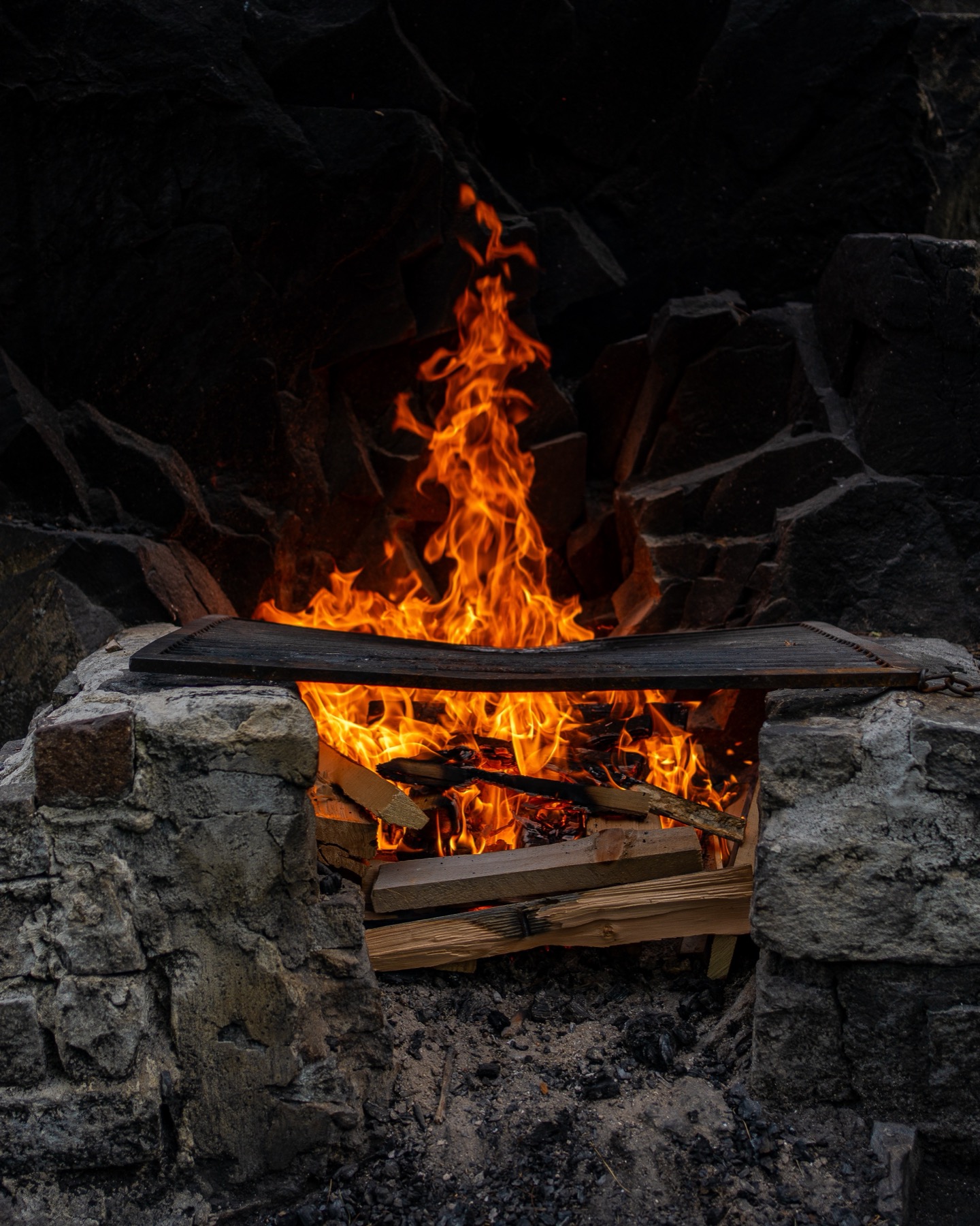 Close-up of flames in a stone fire pit at dusk