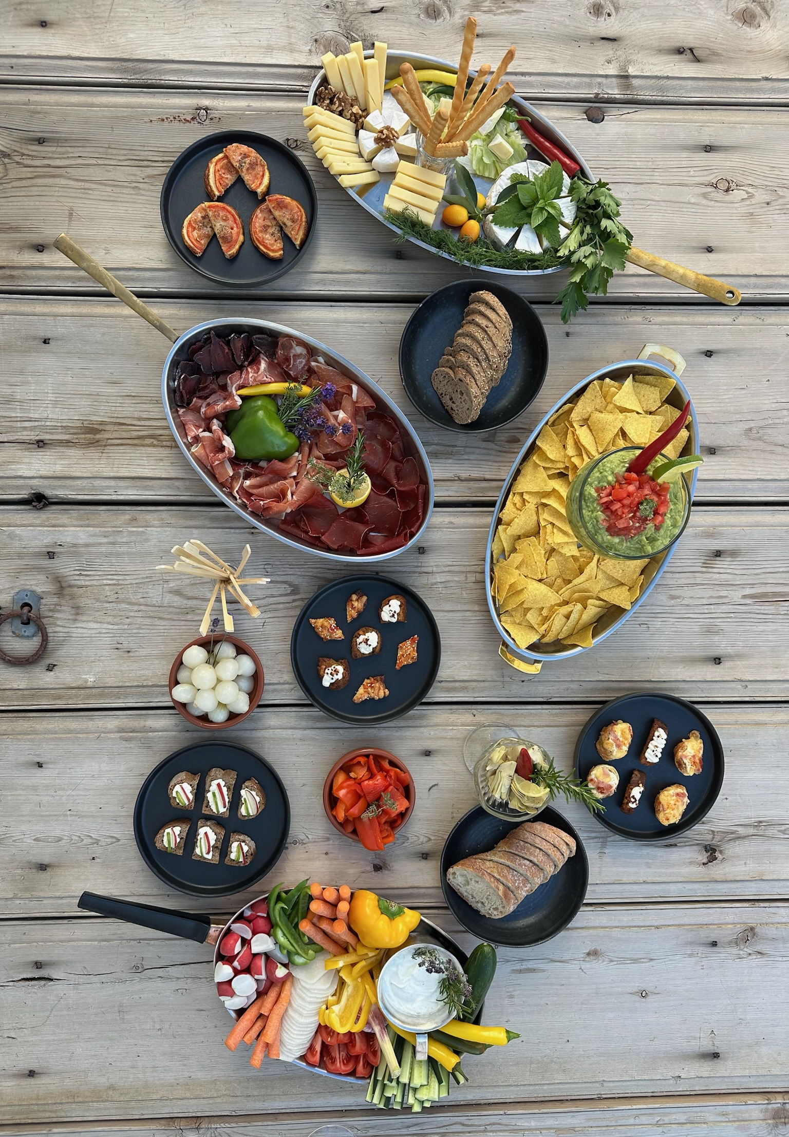 Aperitif spread of charcuterie, cheese, and dips on the garden terrace